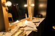 © Mediaphotos - Close up of cluttered vanity table backstage with make up and script papers lit by warm lamp light copy space