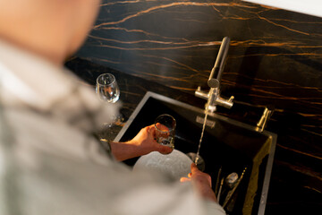 close-up of young guy in love in the kitchen washing the dishes after dinner