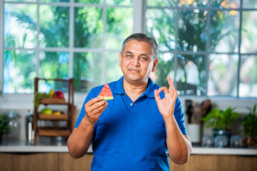 Wall Mural - Indian asian man eating watermelon slice or tarbuj at home