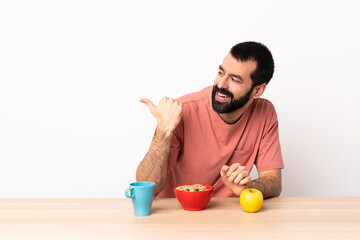 Wall Mural - Caucasian man having breakfast in a table pointing to the side to present a product.
