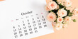 Flat desk paper calendar for October 2024, top view. Pale delicate roses on a beige background.