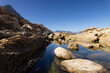 © Wavebreak Media - Rugged rocks surround calm water reflecting blue sky, copy space