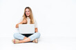 © luismolinero - Young woman with laptop sitting on the floor isolated on white background giving a thumbs up gesture