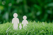 White paper family cut out on green grass background. Family life insurance concept