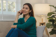A beautiful Asian woman is using a communication device to talk to long-distance friends abroad, Relax on the couch at home and do your own recreational activities.