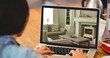 Image of person using laptop with house sitting room interiors displayed on screen