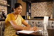 © Wavebreak Media - Indian young woman wearing yellow saree, writing in notebook at home