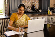 © Wavebreak Media - Indian young woman wearing traditional sari, working on a laptop at home