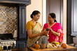 © Wavebreak Media - Indian mother and teenage daughter in traditional attire cook at home