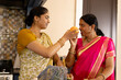 © Wavebreak Media - Indian mother and teenage daughter at home, wearing traditional clothes, holding orange
