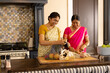 © Wavebreak Media - Indian mother and teenage daughter, wearing traditional sarees, cooking together at home