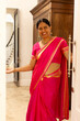 © Wavebreak Media - Indian woman wearing bright pink sari, welcoming guests at home