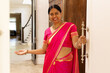 © Wavebreak Media - Indian woman welcoming someone into her home, wearing bright pink sari