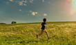 Boy running happily through a nice green meadow during a sunny day