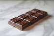 A bar of chocolate sits temptingly on a clean, white surface, its rich aroma wafting through the air