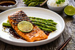 Grilled salmon steak with green asparagus in teriyaki sauce on wooden table
