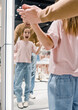 Young Girl Trying on Clothes With Parent in Department Store Mirror Reflection