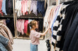 Young Girl Browsing Clothing Racks at a Retail Store During a Shopping Trip