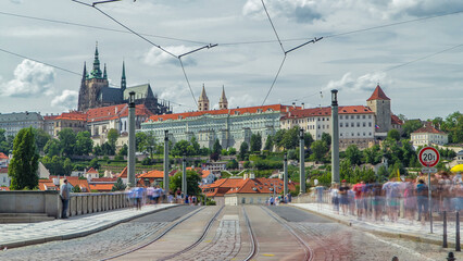 Poster - Red tram passing on Manes Bridge timelapse and famous Prague Castle on the background in Prague, Czech Republic.