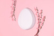 Happy Easter composition. Fluffy willow twigs and an Easter egg-shaped frame on pastel pink background. Top view. Flat lay