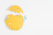 Easter decor concept. Frame made in shape of an Easter egg with colorful Easter eggs and sugar sprinkled candies on white background. Top view. Flat lay.