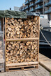A frame of firewood stacked by a houseboat.