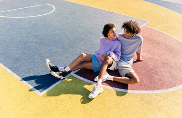 Wall Mural - Interracial young couple dating outdoors, colored and modern urban background