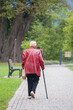 An elderly woman walks with a cane.