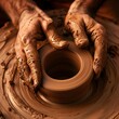 hand are meticulously shaping wet clay into a vessel on a spinning pottery wheel, epitomizing the art of pottery.