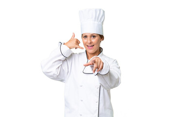 Wall Mural - Middle-aged chef woman over isolated background making phone gesture and pointing front