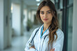 © marishatti - A woman in a white coat with a stethoscope is standing in a hallway
