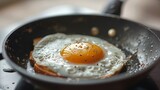 Fototapeta Londyn - Close-up of a skillet with a fried egg cooking over medium heat, with a perfectly set white and a slightly runny yolk, ideal for topping toast.