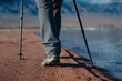 Woman walks along sandy shore of the lake, legs close-up view