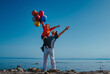 Father holding his son with balloons on shore of the lake on summer day