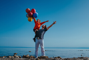 Poster - Father holding his son with balloons on shore of the lake on summer day