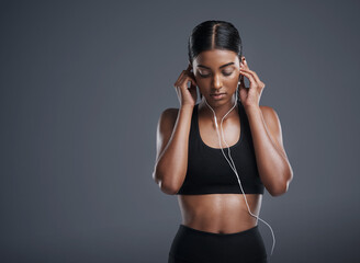 Wall Mural - Woman, fitness and headphones in studio for music, listening and podcast by dark background. Female athlete, streaming and audio for workout, sports training and thinking of playlist on mockup space