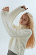 A cute girl in a white sweater poses on a light background in Korean-style photos