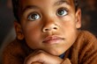 Stunning high resolution photos of a multi-ethnic 7 year old boy, hand under chin, unique eyes looking up, general background kind and dreamy.