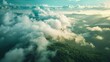 A breathtaking aerial view of a lush mountain landscape partially enveloped in mist and low clouds. Sunlight filters through the clouds, illuminating the rolling hills and valleys with a warm, golden 