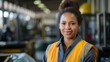b'Portrait of a smiling young African American woman wearing a yellow safety vest in a warehouse'