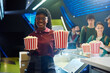Happy black woman selling popcorn in cinema and looking at camera.