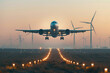 A passenger aircraft taking off with wind turbines in the background, showcasing the juxtaposition of traditional and renewable energy sources.

