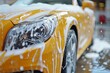 Professional yellow car wash with shampoo foam and water splashes ? auto detailing service