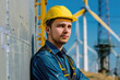 A young male engineer planning and working for the energy industry, standing beside a wind turbine farm power station.

