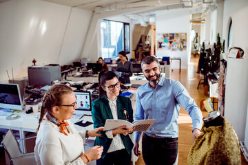 Wall Mural - Team members discussing clothing design in a bright creative office space