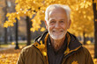 Portrait of a smiling elderly man, a pensioner in an autumn park in sunny weather.