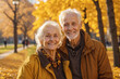 Portrait of a smiling elderly man and woman, a married couple, pensioners in an autumn park in sunny weather.