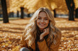 Portrait of a smiling blonde girl in an autumn park on a sunny day.