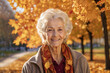 Portrait of a smiling elderly woman, a pensioner in an autumn park in sunny weather