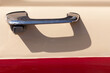 Door handle of a retro car close-up. chrome lock, door painted beige and red